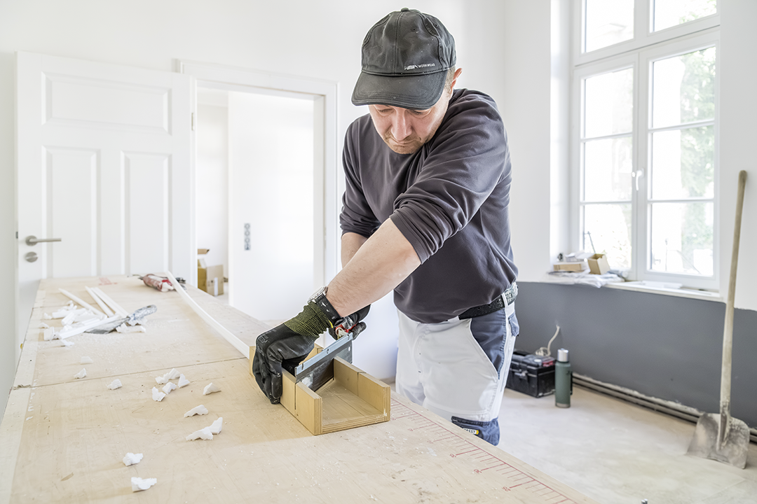 Ein Mitarbeiter von Malzeit schneidet eine Stuckleiste zu